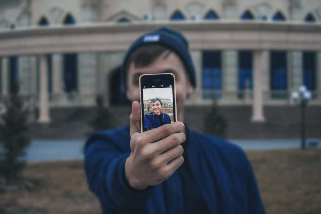 a young guy taking a selfie in front of building
